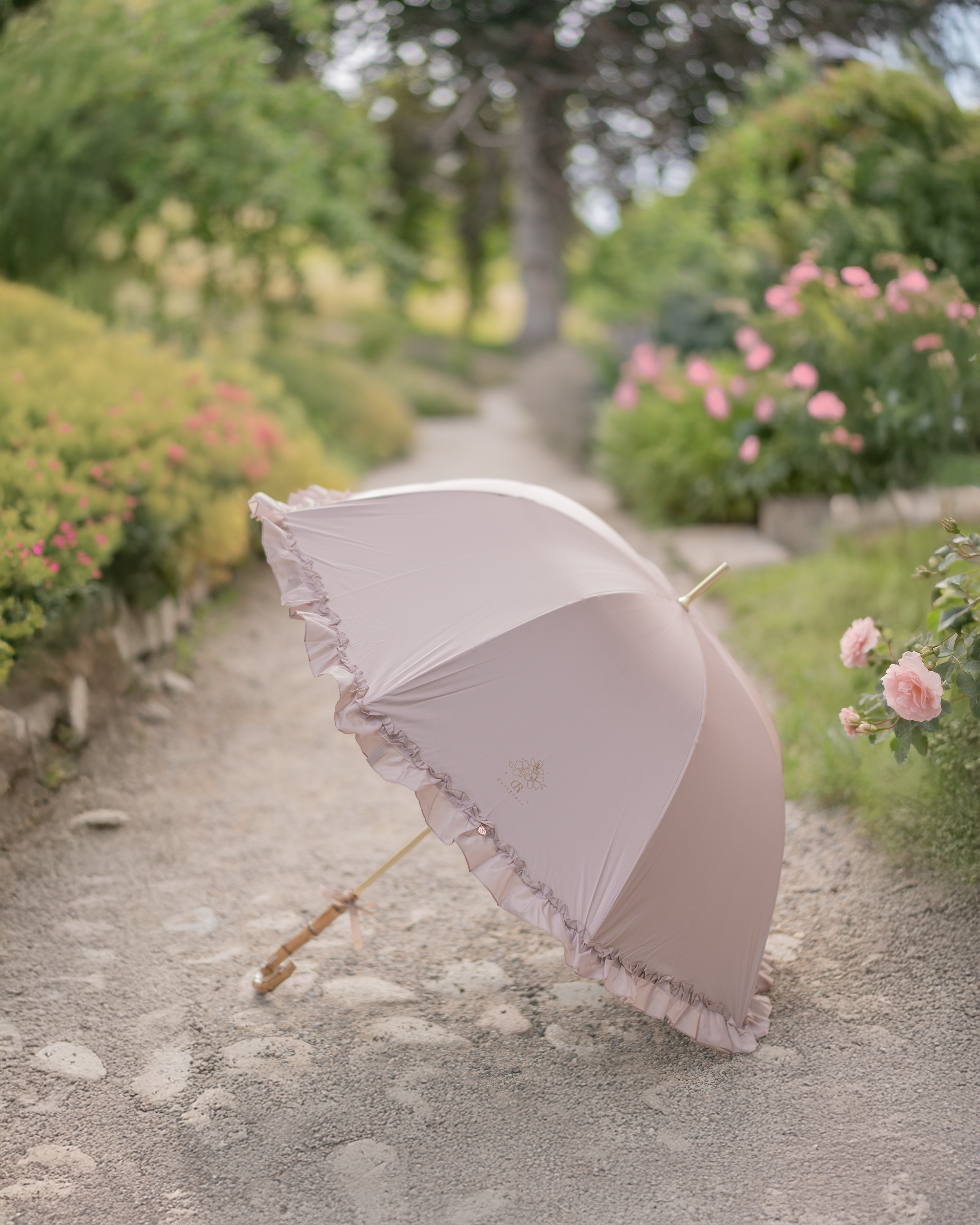 Dusty Rose umbrella on a garden path with flowers and greenery