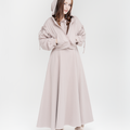 Woman wearing a hoodie with bows and a dusty rose long dress on a white background