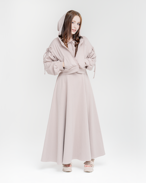 Woman wearing a hoodie with bows and a dusty rose long dress on a white background