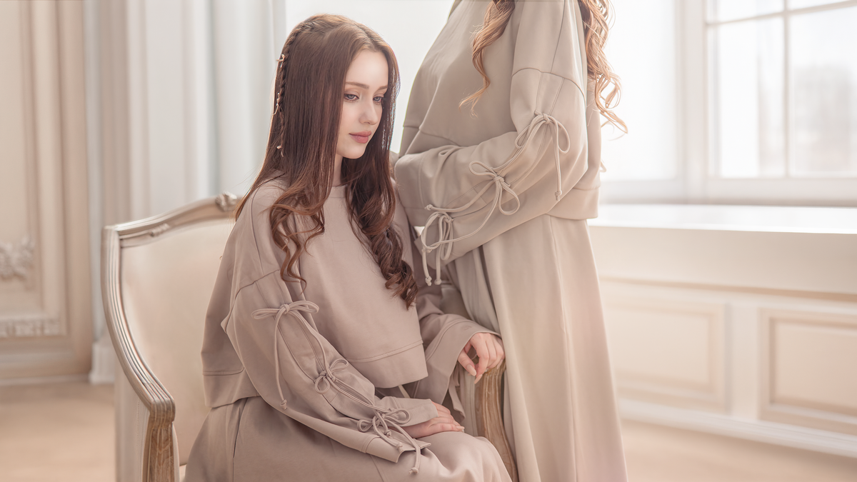 Two women in light-colored romantic clothing set in a softly lit room.
